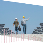 Two people in hardhats working near solar panels
