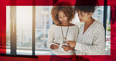 Two African-American business women in a meeting room looking at a tablet